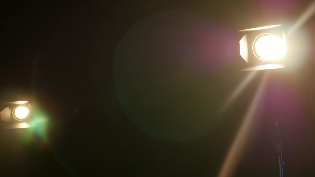 Two people setting up the scene for an interview, they are moving the lights left and right