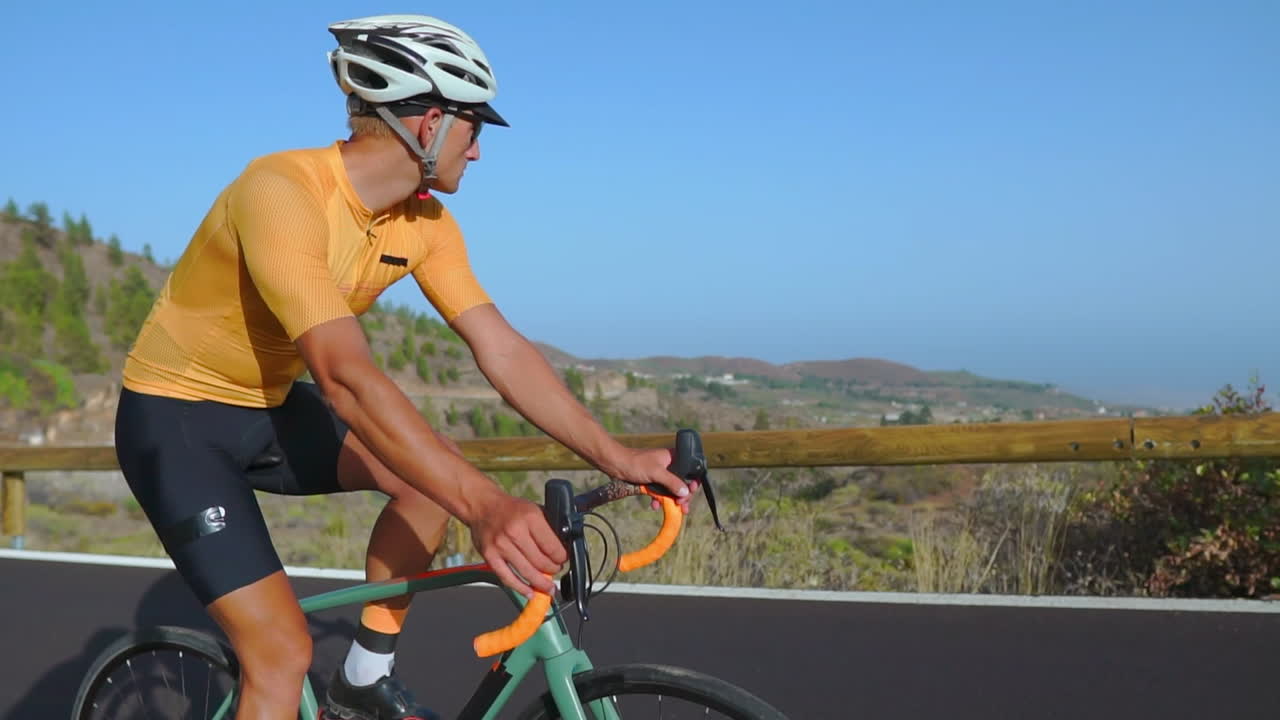 con una carretera vacía por delante, un hombre monta su bicicleta de carretera durante la mañana, entregándose al ejercicio al aire libre. la grabación a cámara lenta aumenta la experiencia de los deportes extremos
