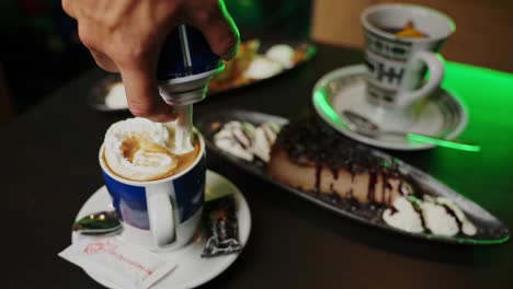 poniendo crema batida en una taza de vidrio con café espresso