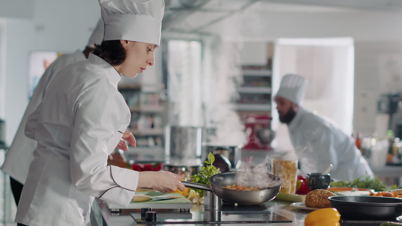Female cook making professional culinary dish in frying pan