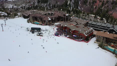 winter skiing resort complex with people sliding during snowfall, aerial drone view