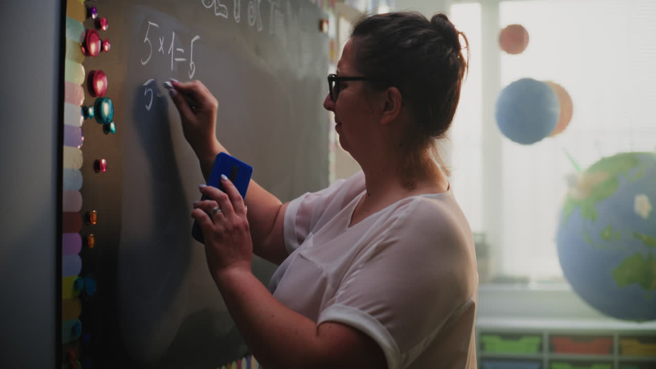 Teacher writing on a blackboard in a classroom