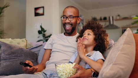 father and daughter watching tv with popcorn