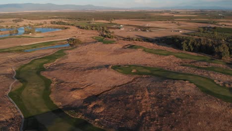 Aerial-view-of-California-golf-course,-which-is-perfectly-green,-and-the-surrounding-drought-conditions