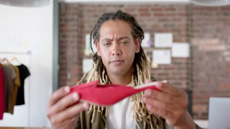 retrato de un feliz diseñador masculino biracial inspeccionando un zapato en un estudio de diseño de moda, en cámara lenta.