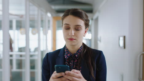 beautiful-business-woman-using-smartphone-walking-through-office-texting-sending-emails-successful-female-executive-checking-messages-on-mobile-phone-arriving-at-workplace-4k