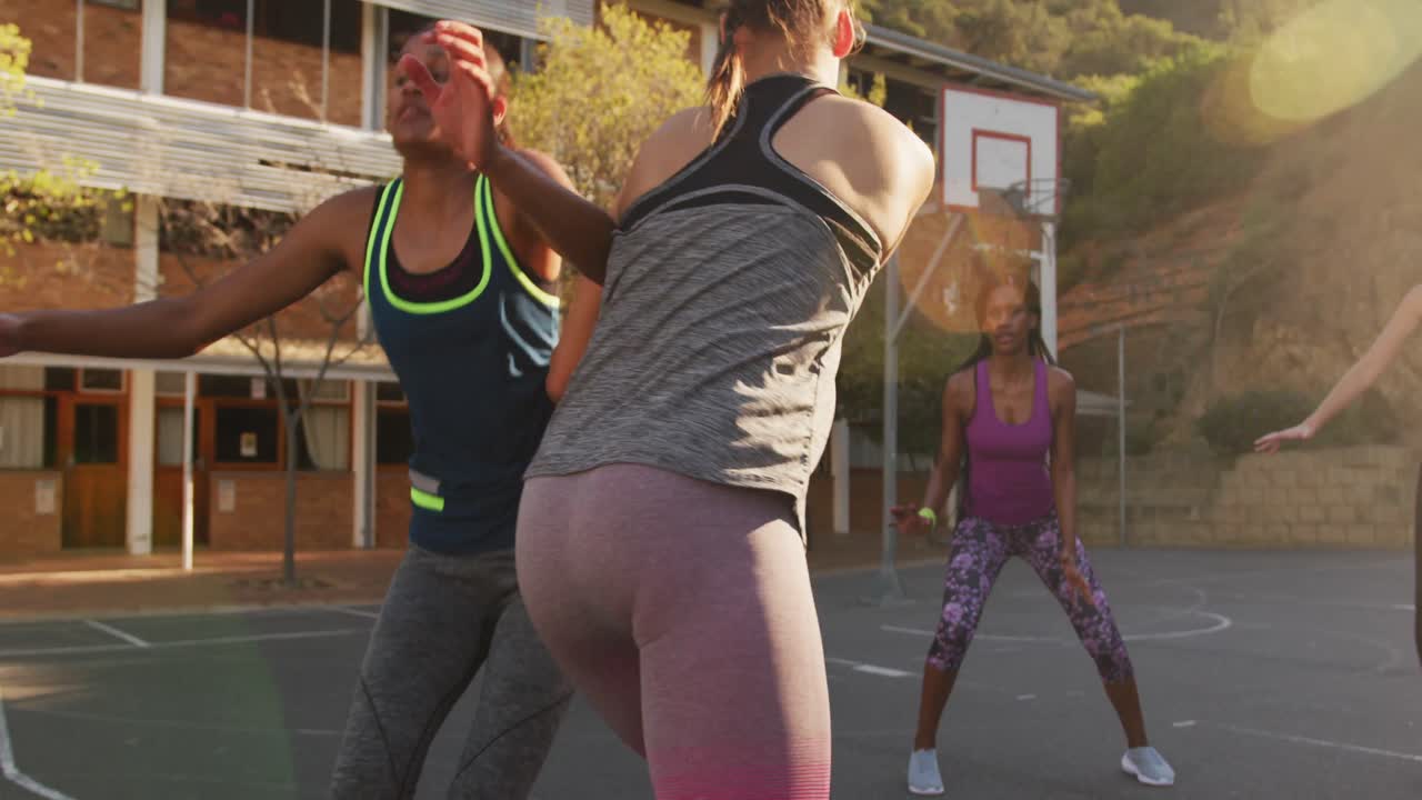 Diverse female basketball team playing match, dribbling and shooting ball