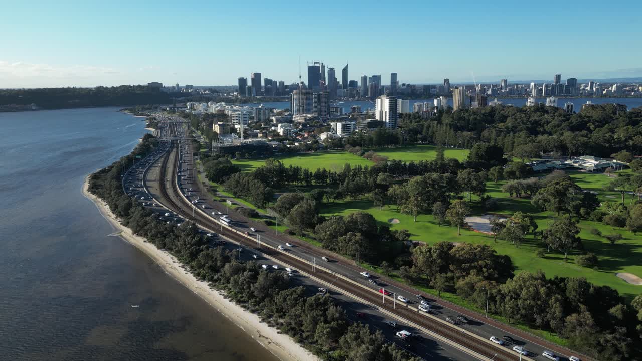 fotografía de avión no tripulado de la intersección costera muy frecuentada al lado del campo de golf y el horizonte de perth en el fondo - hermoso día soleado en australia