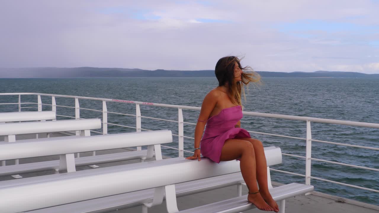 Sexy Young Woman In Pink Dress Sitting On Chair At Ferry Deck - Ferry Boat Heading To Island Of North Stradbroke In QLD, Australia
