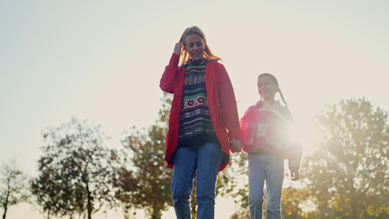 Mother and daughter walking hand in hand in the park