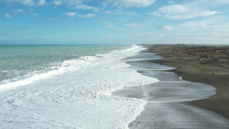 aerial slow-motion above white-water patterns at vast kaitorete spit with turquoise-colored south pacific ocean