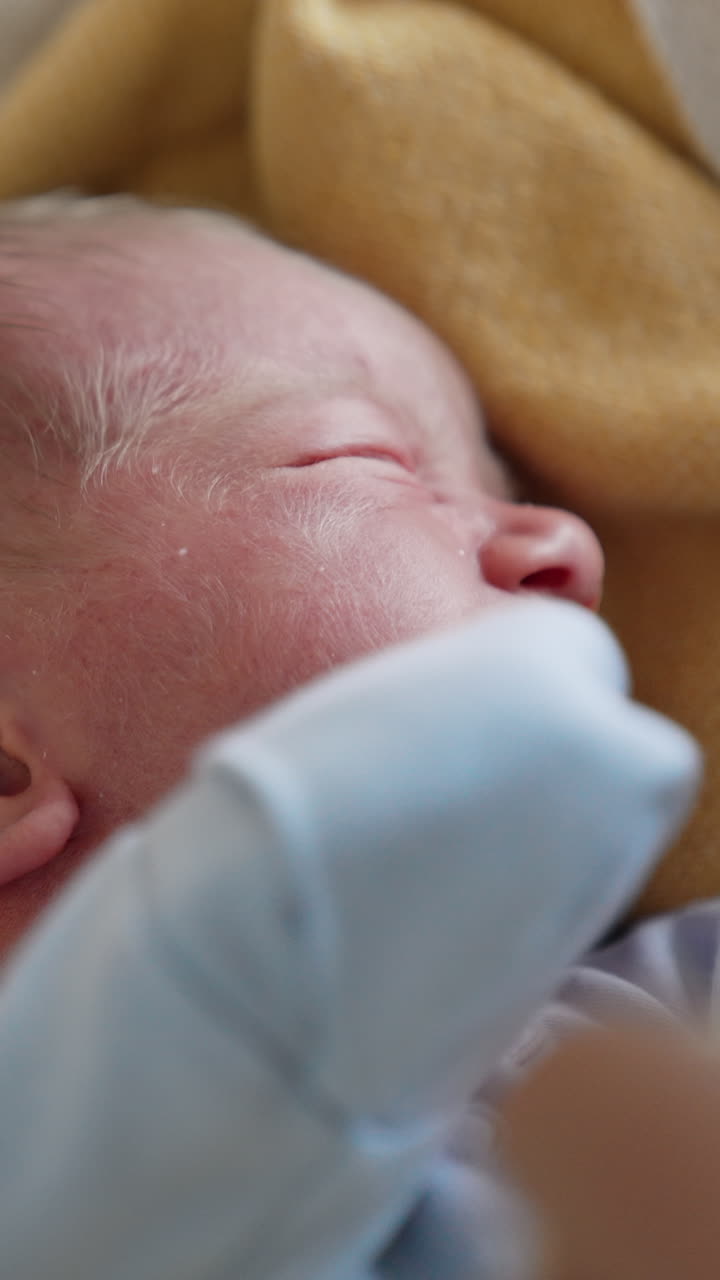 Menino jovem adorável deitado na cama. Retrato de bebê recém-nascido. Vídeo vertical