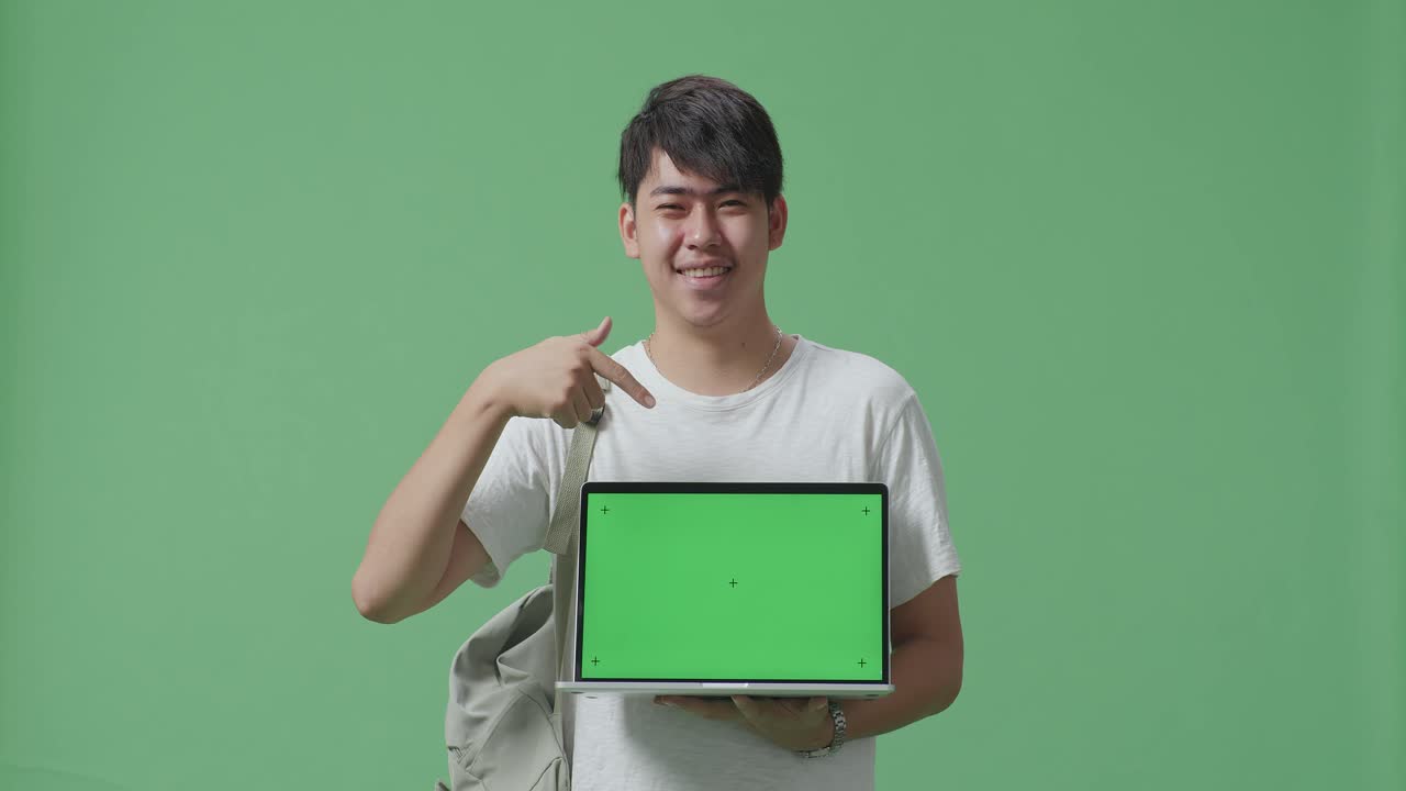 초록색 화면 을 가진 노트북 을 선보이는 학생