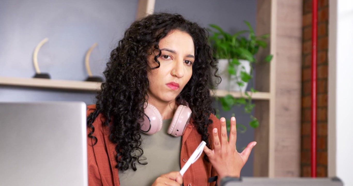 African American woman with pink headphones tapping pen counting fingers writing on tablet for work