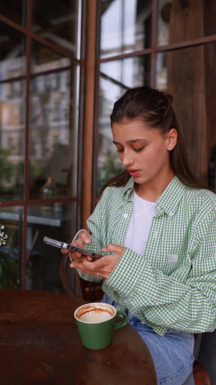 una mujer joven usando el teléfono en un café.