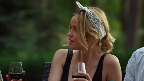 surprised girl having chat with friends outside. woman holding glass of wine