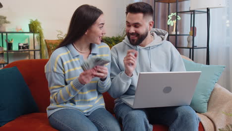 smiling happy family counting money cash and use laptop calculate domestic income earnings at home