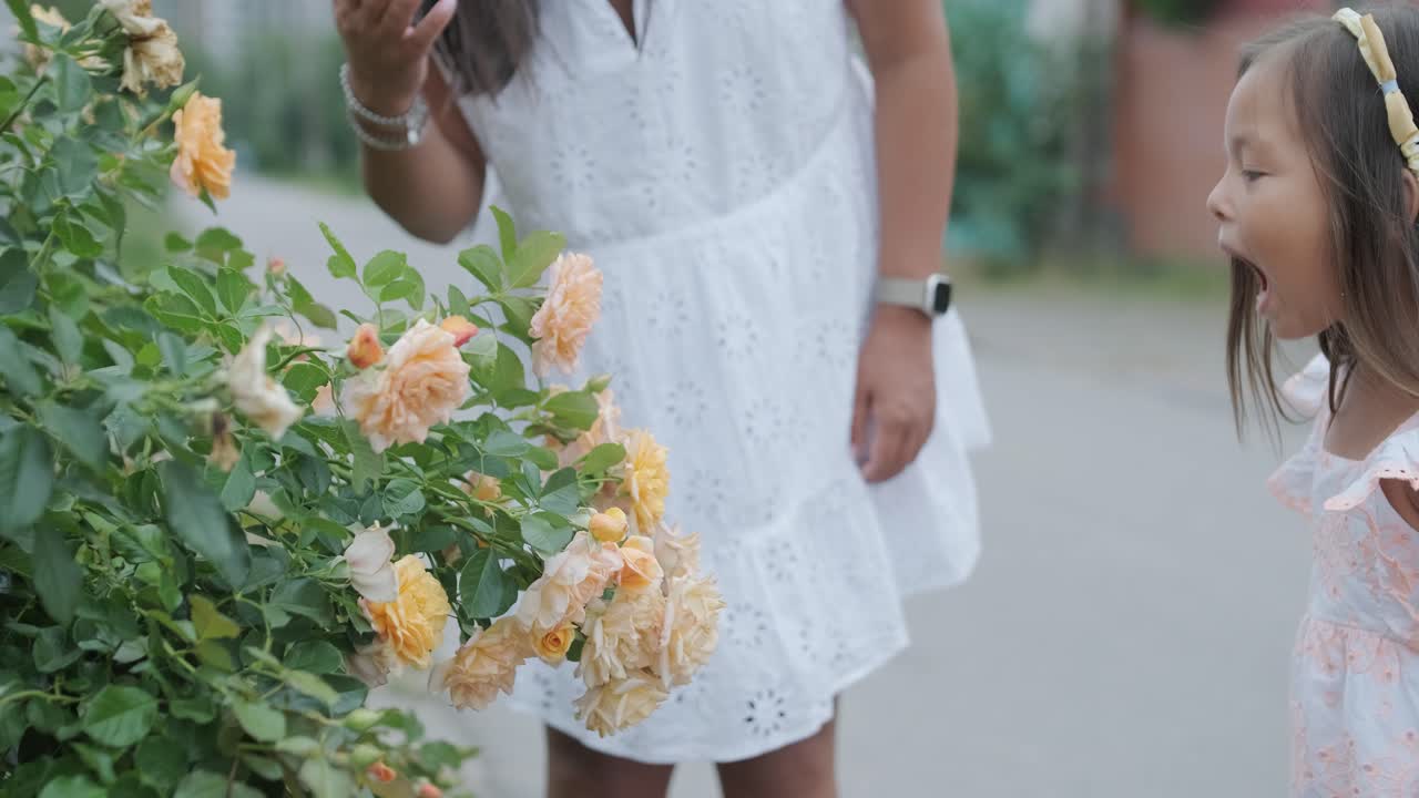 niña admirando flores con su madre