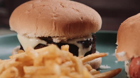 hand putting bun on top of no meat cheeseburger with french fries chips