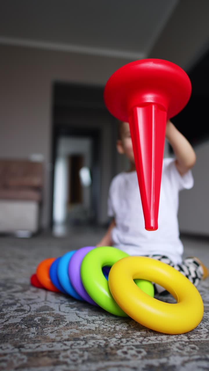 Caucasian baby boy pulls the basis from the pyramid toy. Happy smiling kid playing with toys at home.