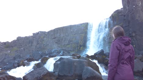 rear view of caucasian women standing near the waterfall and enjoying the view