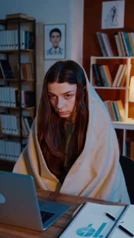 woman studying late at night under a blanket