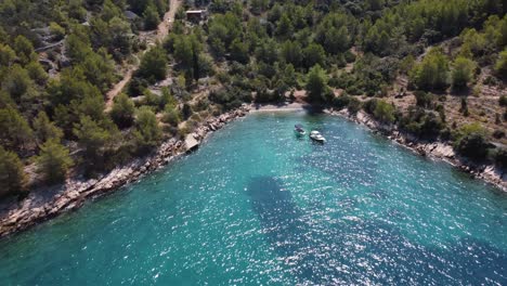 aerial fly away shot of secluded private beach with anchored boats over the beautiful turqoise waters of adriatic sea in brac, croatia