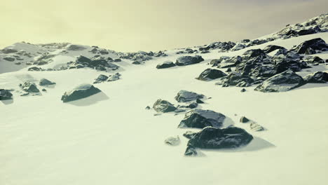 snowy mountain landscape with rocks under a soft afternoon sky