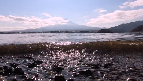 Low-angle-view-of-small-waves-crashing-on-pebble-beach-with-Mt