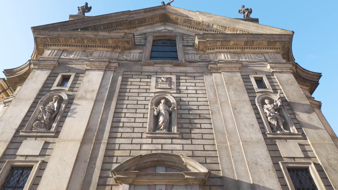 Movimento de câmera para cima ao longo da Igreja de São Francisco de Assis em Praga, focando em suas características arquitetônicas góticas e barrocas