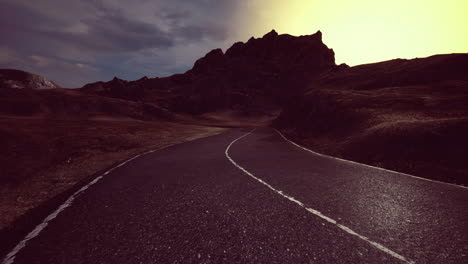 Winding road leading toward majestic mountains at dawn with vibrant colors