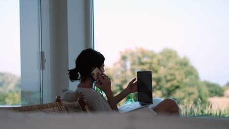 freelancer's day: casual businesswoman working by the window, sunlit room