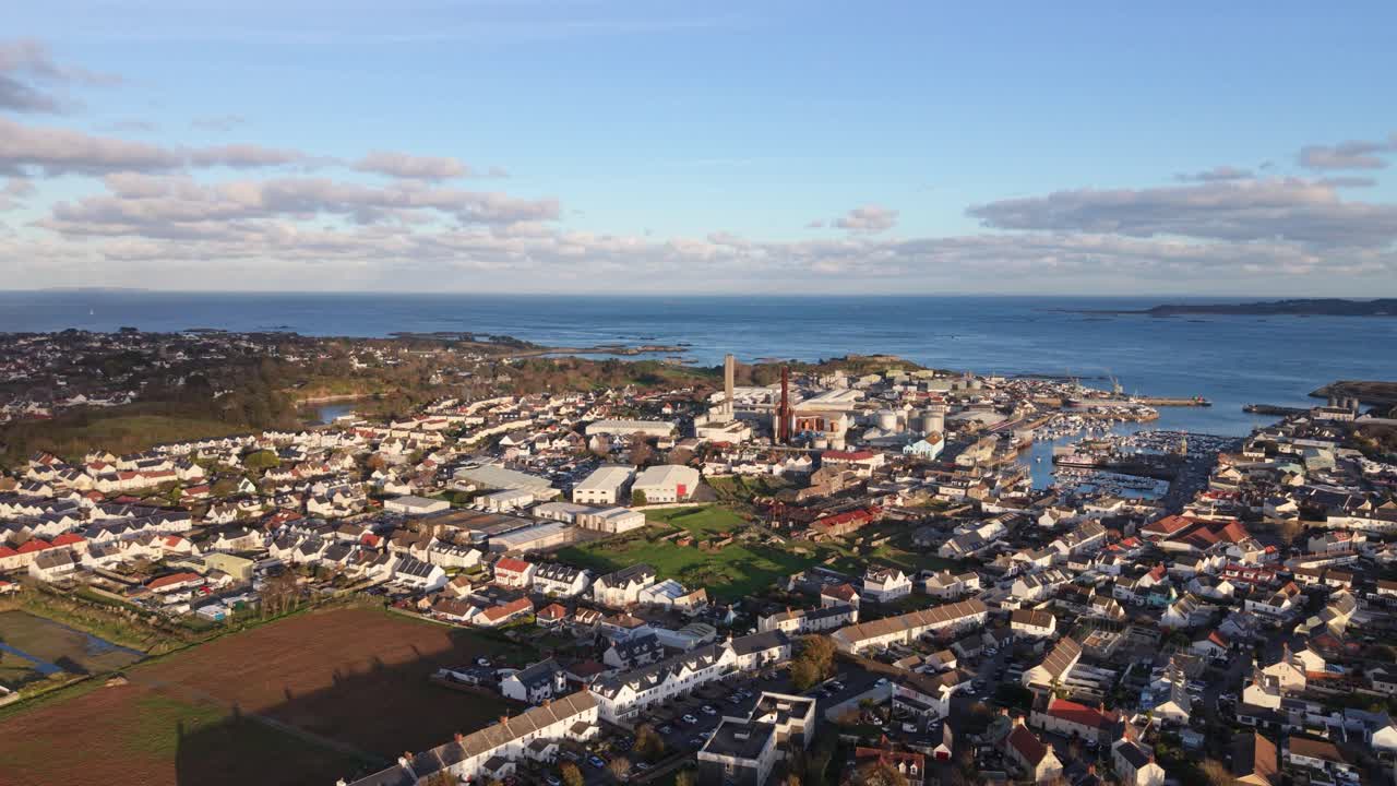 St Sampson Guernsey, vista panoramica dall'alto con drone su St Sampson dal porto oltre la centrale elettrica e verso nord sotto il sole dorato del pomeriggio con il Castello di Vale e Herm sullo sfondo