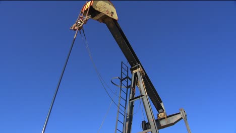 low angle view in an oilfield of an oil derrick pumping