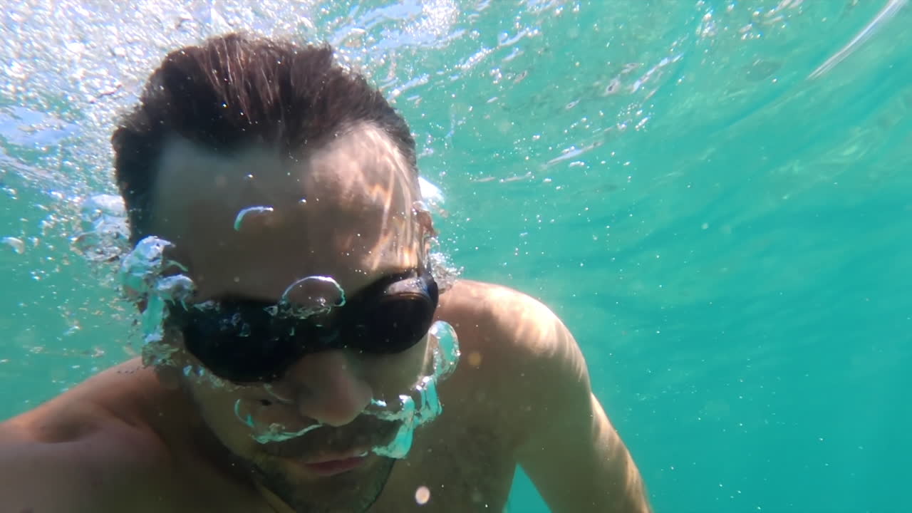 Man swimming underwater in the ocean with black goggles
