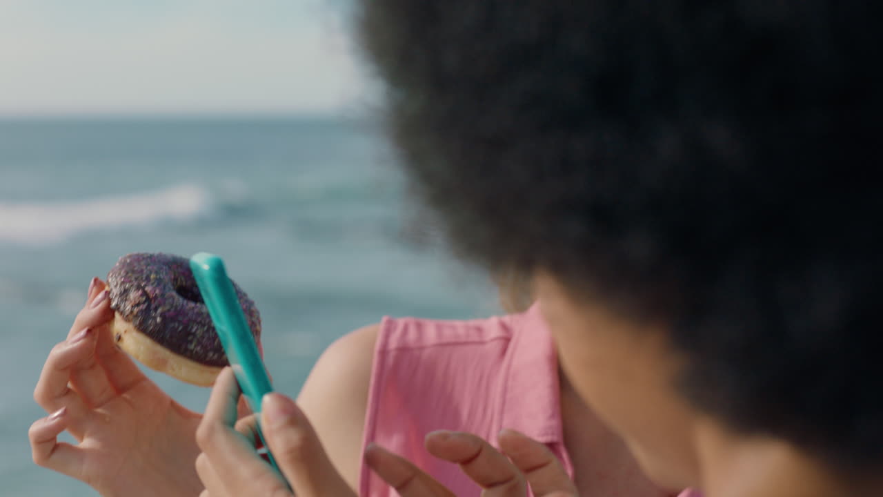 two young women friends looking at photos on smartphone enjoying sunny day on beach 4k footage
