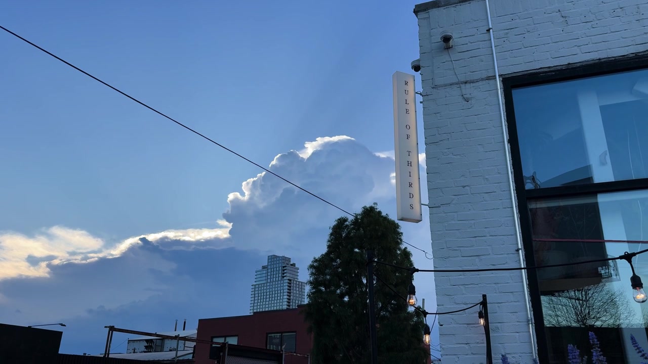 Urban street view with dramatic clouds and sunlight behind city buildings in Brooklyn