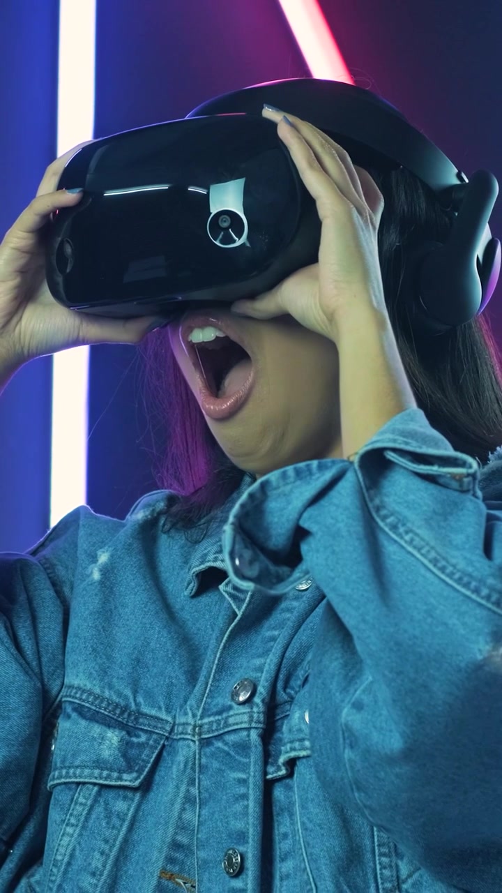 Giovane donna con visore per la realtà virtuale in uno studio al neon