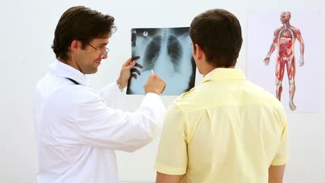Lächelnder-Arzt,-Der-Mit-Dem-Patienten-Das-Röntgenbild-Betrachtet