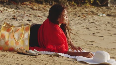 Chica-Latina-Descansando-En-Su-Frente-Se-Mueve-Para-Ponerse-Cómoda-Acostada-En-La-Arena-De-La-Playa