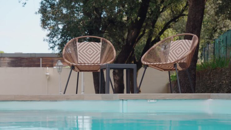 Slow orbiting shot of garden furniture sitting beside a private pool
