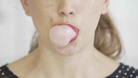 close-up-of-blonde-caucasian-young-girl-with-red-lips-chewing-gum-and-blowing-bubbles-,-hipster-pop-footage,-black-shirt