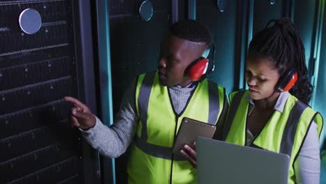 african american computer technicians using laptop working in business server room