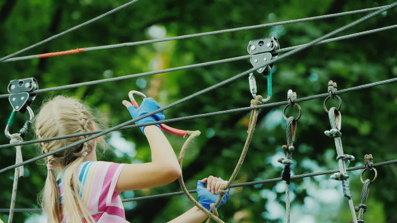 entretenimiento en el campamento de verano - un niño aprende a usar cables de seguros trepa alto en las ramas de