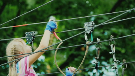 entertainment in summer camp - a child learns to use insurance cables climbs high in the branches of