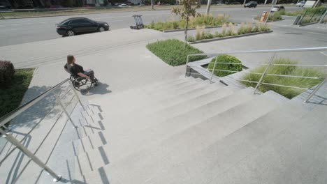 a woman in a wheelchair moves along a city sidewalk near a set of stairs, highlighting the challenges of accessibility in urban environments. the image emphasizes mobility and inclusive infrastructure design.