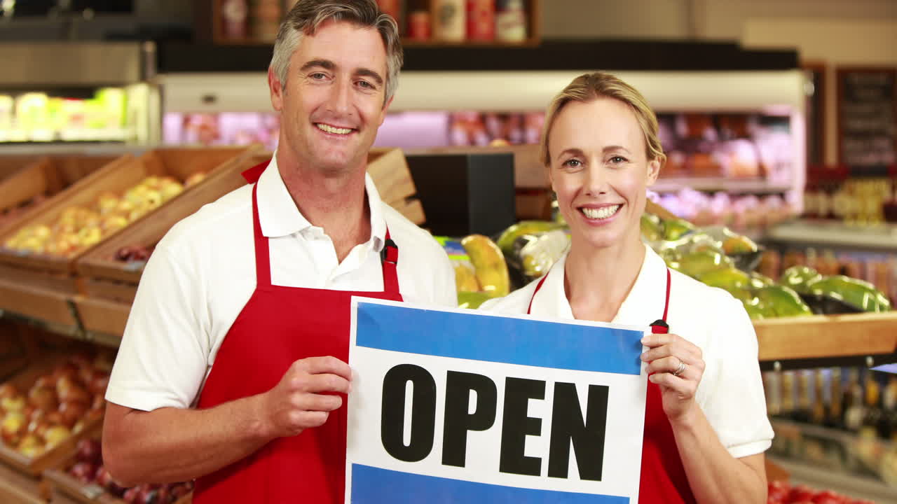 Smiling workers holding open sign