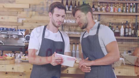 animación de signos y números de moneda, compañeros de trabajo caucásicos discutiendo sobre la tableta en un café