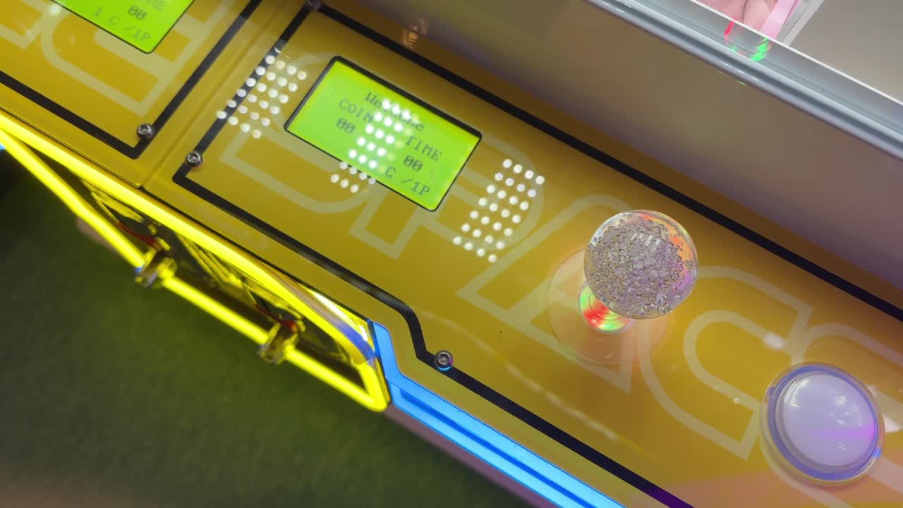 Primer plano de una palanca de mando de un videojuego arcade y una pantalla digital de monedas con coloridas luces de neón
