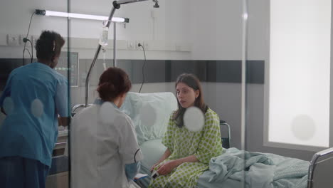 sick woman talking with doctors while sitting on bed during sickness recovery